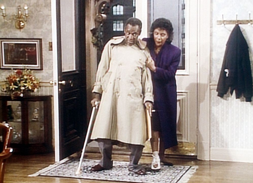 Clair (Phylicia Rashad, r.) hat sich den Zeh gebrochen, so dass Cliff (Bill Cosby, l.) ihre Krücken tragen muss, während er ihr als Stütze dient. - Bildquelle: Viacom