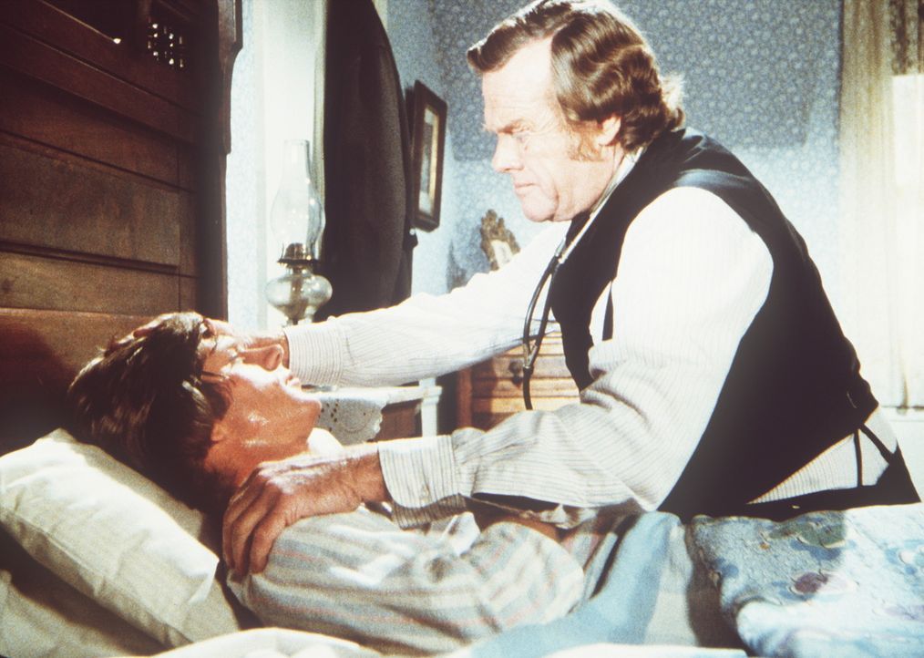 Dr. Baker (Kevin Hagen, r.) behandelt Almanzo Wilder (Dean Butler, l.), der an Diphterie erkrankt ist. - Bildquelle: Worldvision