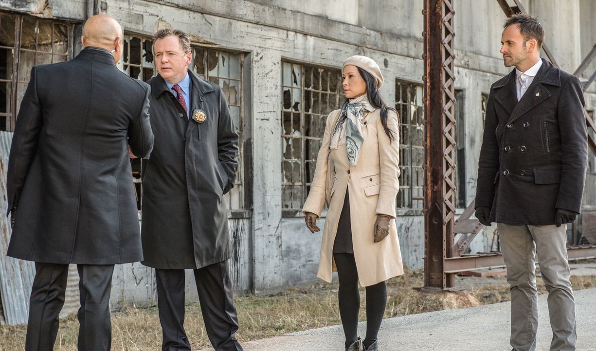 Capt. Gregson (Aidan Quinn, 2.v.l.), Dr. Watson (Lucy Liu, 2.v.r.) und Sherlock Holmes (Jonny Lee Miller, r.) lernen Moriartys Gefängniswärter Ramse... - Bildquelle: CBS Television