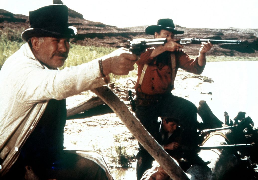 Sam Clayton (Ward Bond, l.) und Ethan (John Wayne, r.) verteidigen sich gegen angreifende Indianer. - Bildquelle: Warner Bros.
