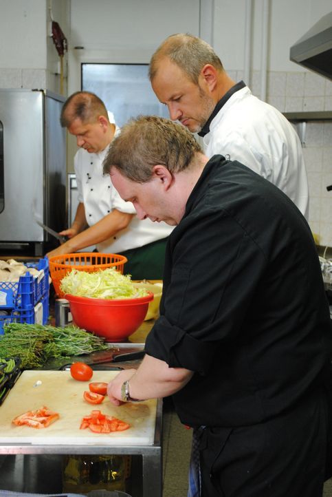 Sternekoch Frank Rosin (hinten r.) beobachtet Jens (vorne r.) und Uwe (l.) bei der Arbeit in der Küche und gibt ihnen wichtige Tipps. - Bildquelle: kabel eins