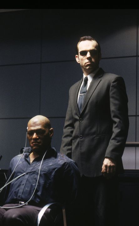 Agent Smith (Hugo Weaving, r.) foltert Morpheus (Laurence Fishburne, l.), um herauszukriegen, wo die geheime Stadt der Menschen ist. - Bildquelle: Warner Bros. Pictures