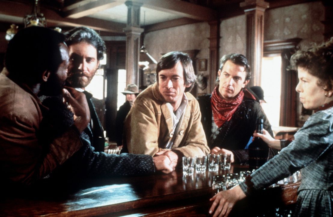 Mal (Danny Glover, l.), Paden (Kevin Kline, 2.v.l.), Emmett (Scott Glenn, M.) und Jake (Kevin Costner, 2.v.r.) werden im Saloon von Silverado von de... - Bildquelle: Columbia Pictures
